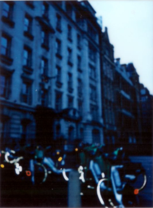 A blue-toned dusk street with a row of bikes and tall buildings